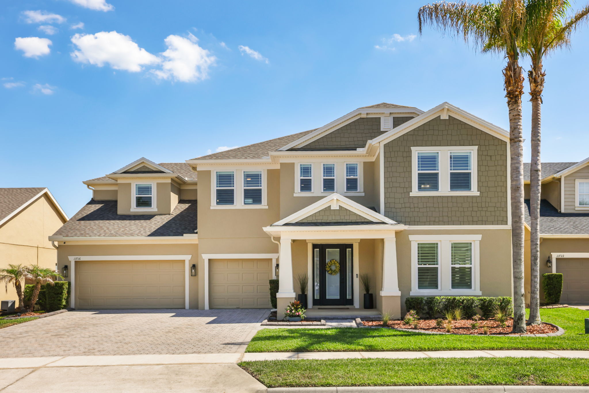 Front elevation of 11716 Sheltering Pine Drive with palm trees and three-car garage